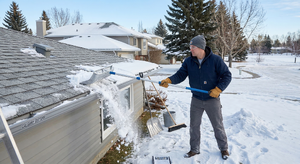 Proper stance and pulling technique for using a roof rake to remove snow safely